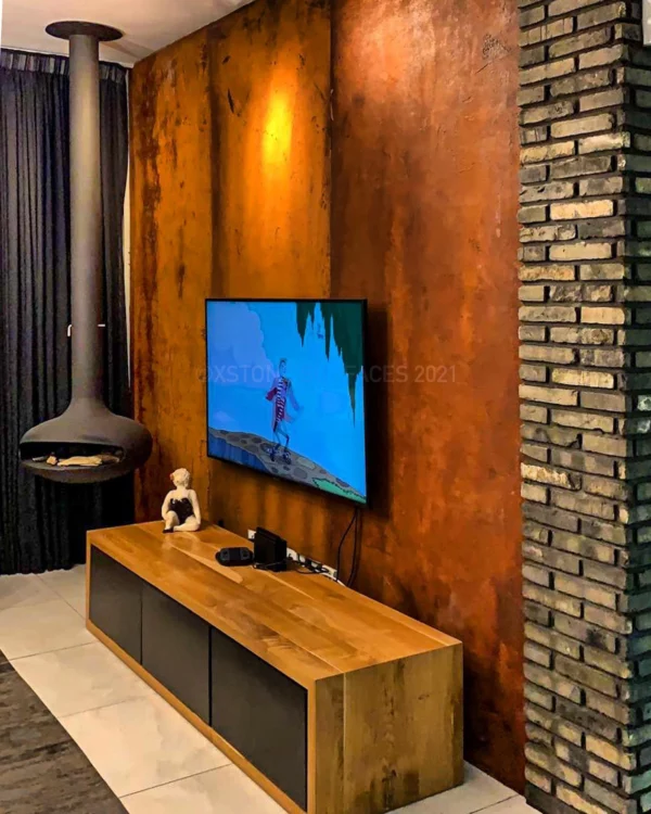 XSTONE Wall - 022 Veneer Rust Smooth on a wall behind a wood stove and a telivision in a living room